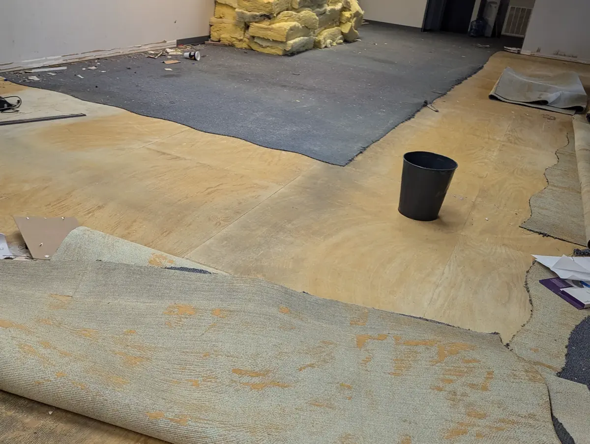 Old flooring rolled back in a commercial space, exposing the floor underneath before preparation