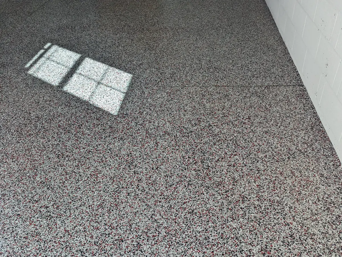 A finished decorative flake floor in a garage, blended from white, black, grey and red media